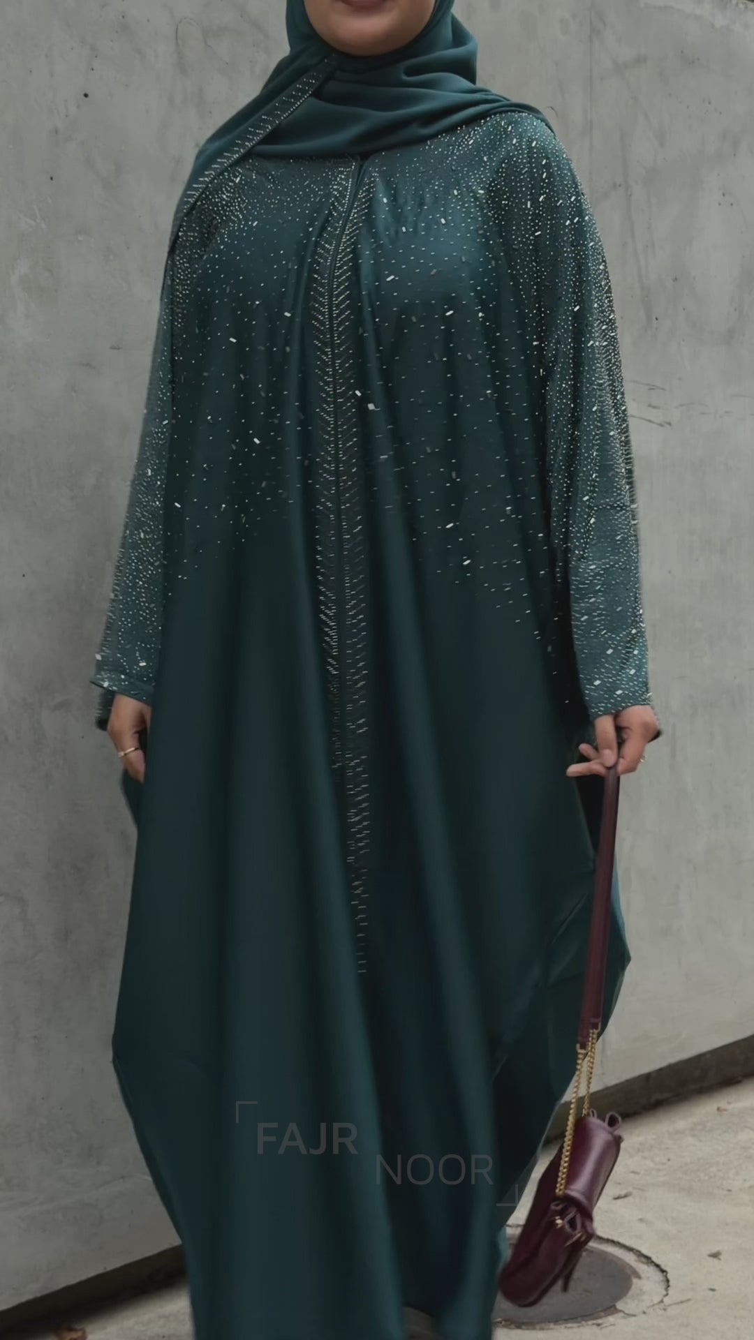 Woman wearing the Fajr Noor Amina Abaya in emerald with embellished detailing and a matching hijab