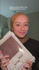 Woman wearing a mustard gold Fajr Noor opaque premium modal hijab, holding packaged modal hijabs during a try-on haul