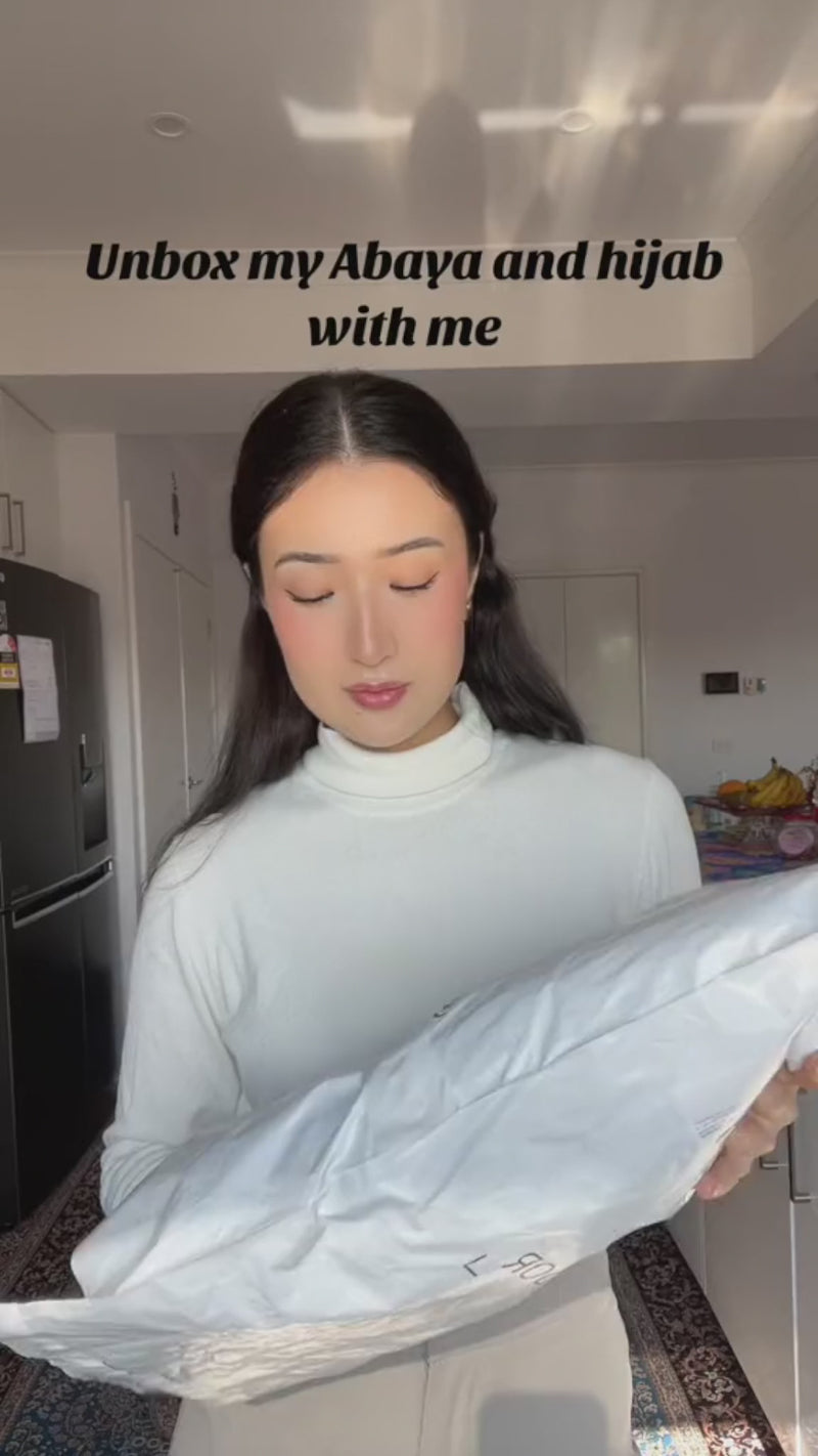 Woman unboxing the Fajr Noor Aisha Abaya in navy with matching hijab
