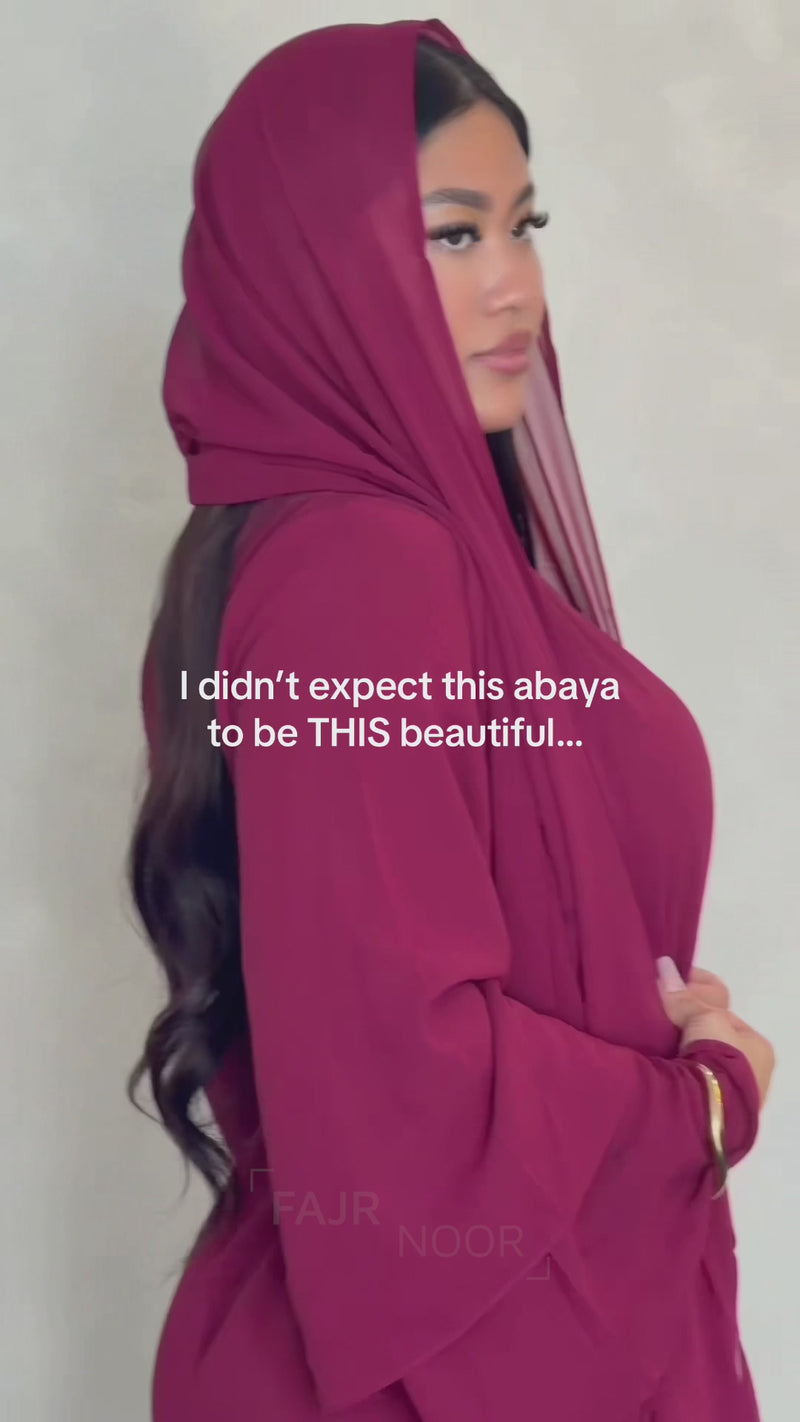 Woman wearing the Fajr Noor Aisha Abaya in maroon with a matching hijab draped over the shoulders